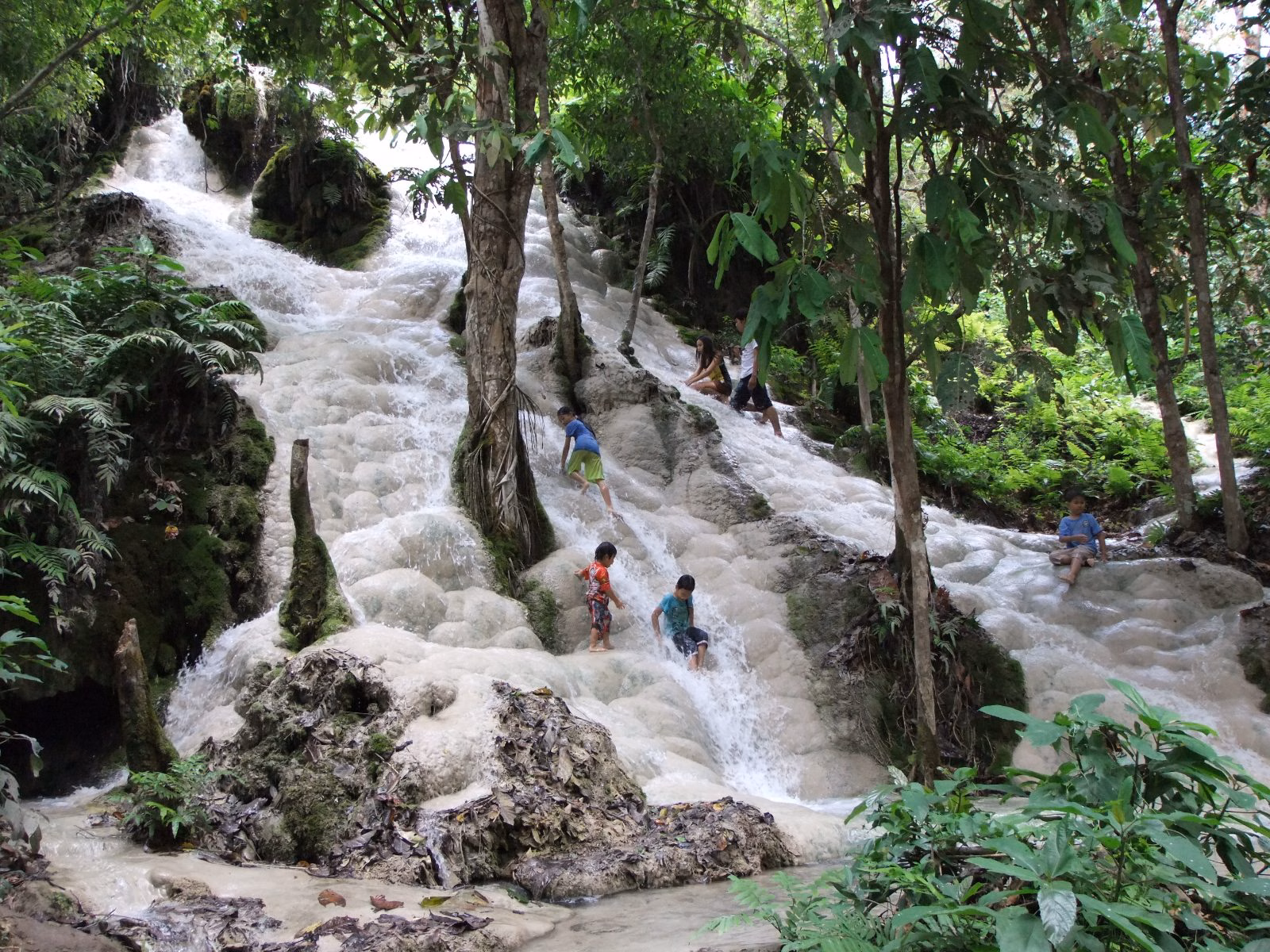 People walking up the white mineral rock of Bua Tong Sticky Waterfall in the forest north of Chiang Mai